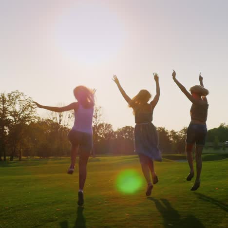 Silhouetten-Von-Unbeschwerten-Jungen-Frauen,-Die-Bei-Sonnenuntergang-Auf-Dem-Rasen-Laufen-1