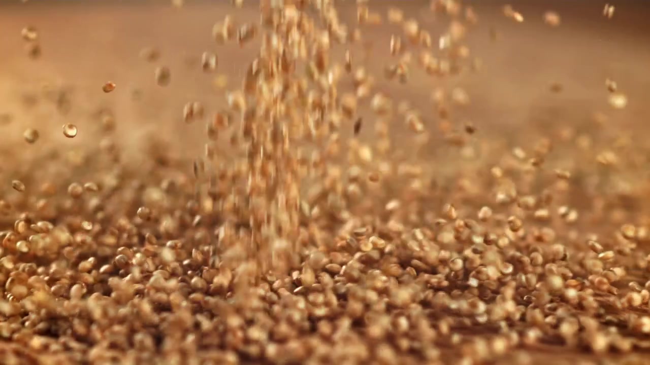 Quinoa-Körner fallen in Zeitlupe auf eine Holzoberfläche