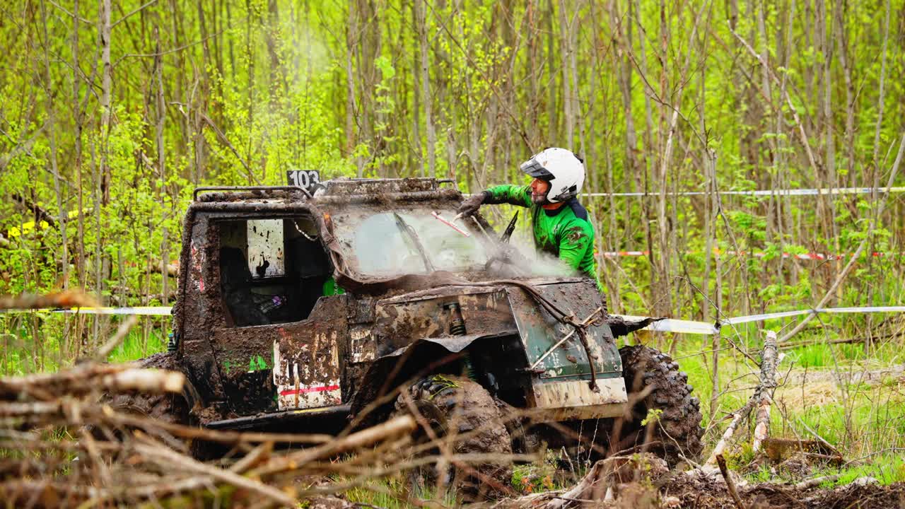 ATV side by side races beside rider in neon, skimming mud surface near tree line