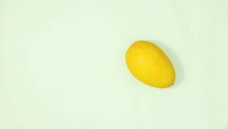 yellow melon rotating on light green background. stop motion flay lay