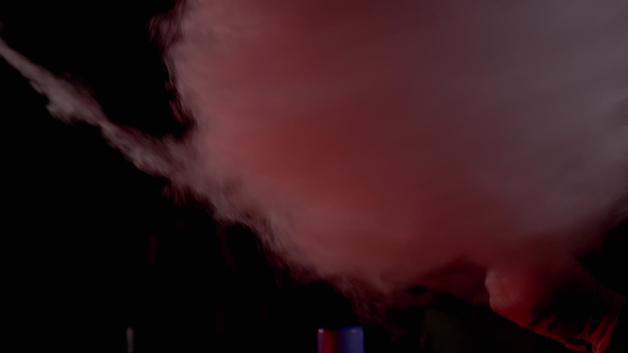 여성의 손은 나무 막대기에 설탕에서 목화 사탕의 공기 구름을 불어넣습니다.