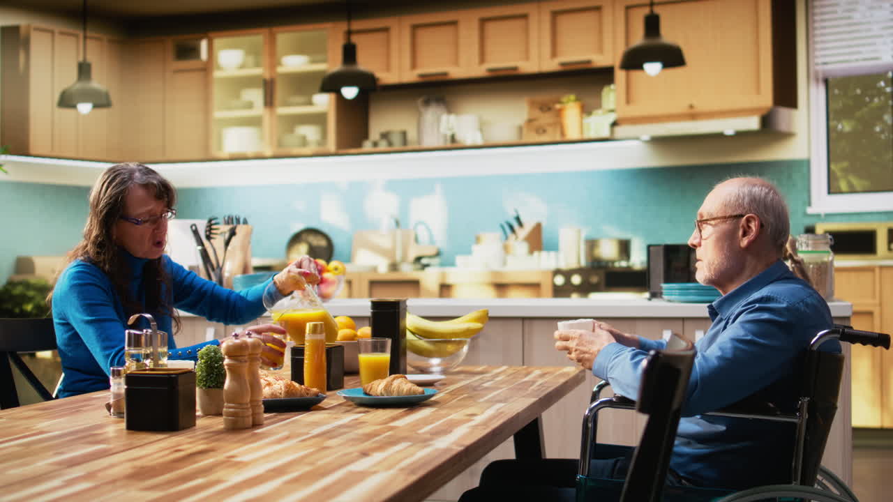 Mature man with physical disability serving coffee and pastry with his wife