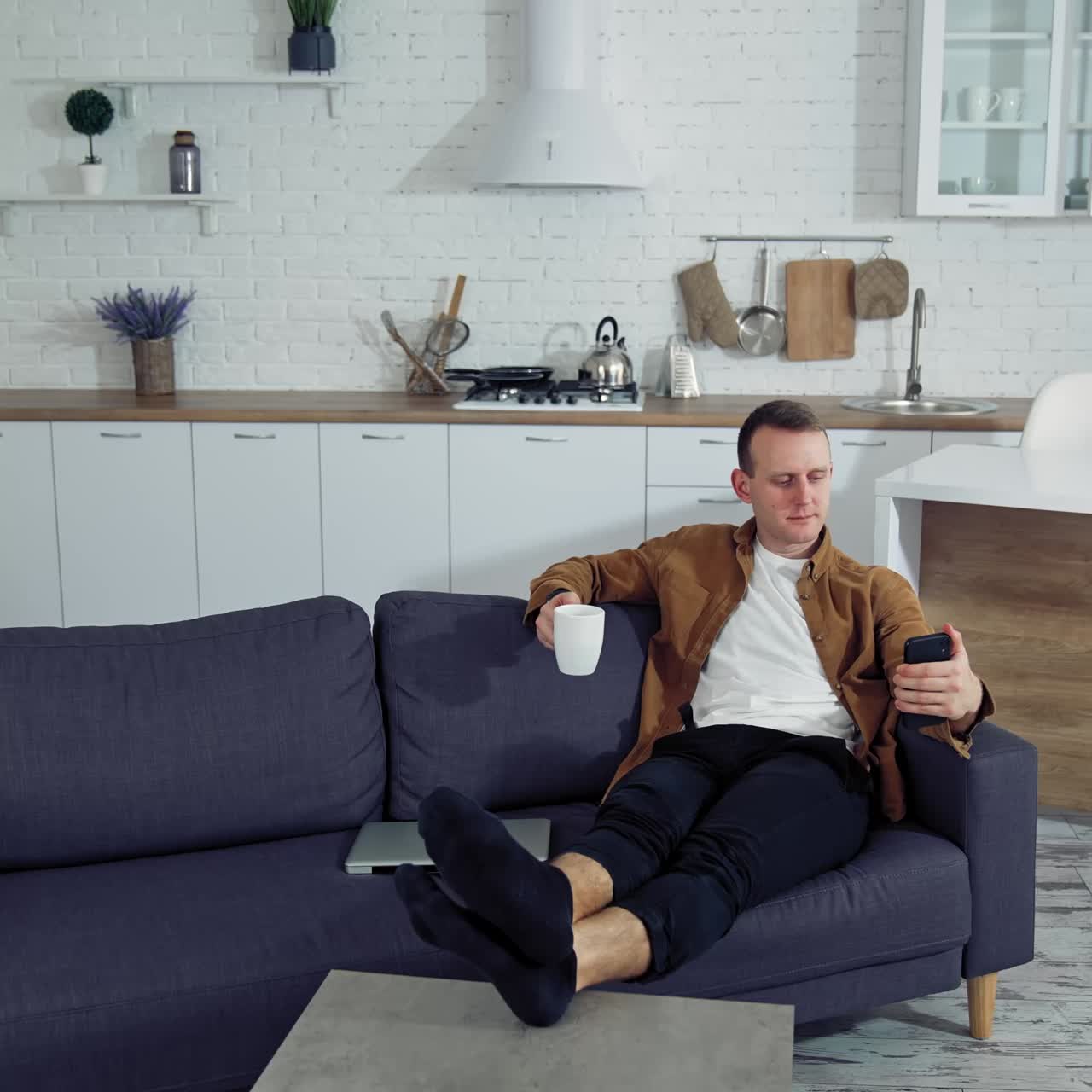 Man using smartphone at home. Young man sitting on sofa, using mobile phone