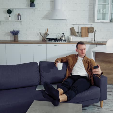 man using smartphone at home. young man sitting on sofa, using mobile phone