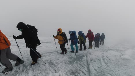 group hiking on glacier in snowy mountains