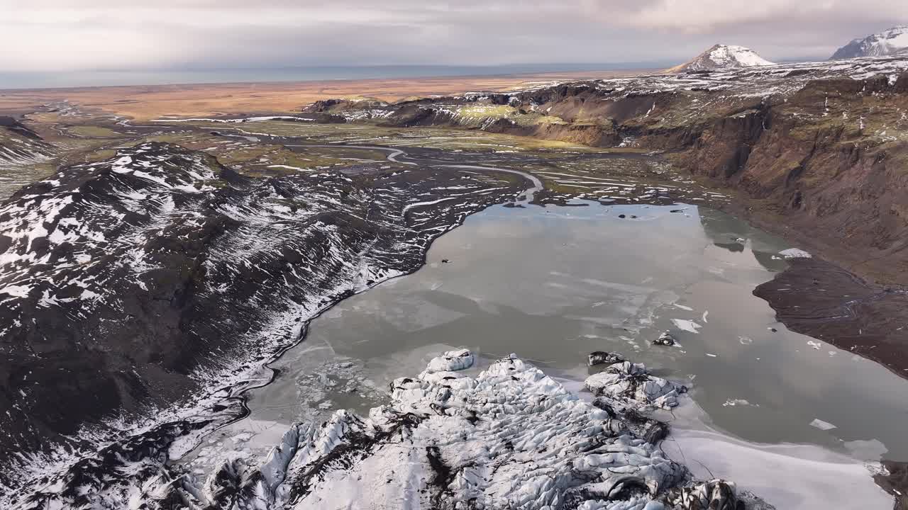 Stunning drone view of Solheimajokull glacier in Iceland, icy formations, frozen lake and rugged volcanic terrain.