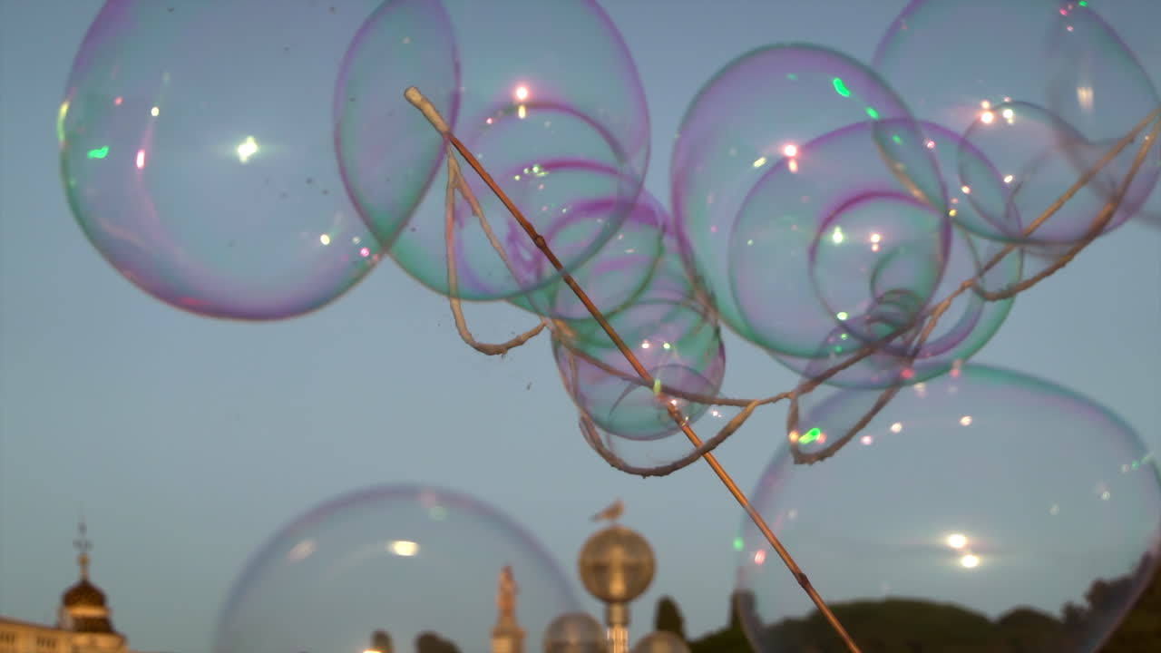 Colorful soap bubbles floating against the blue evening sky during a street performance