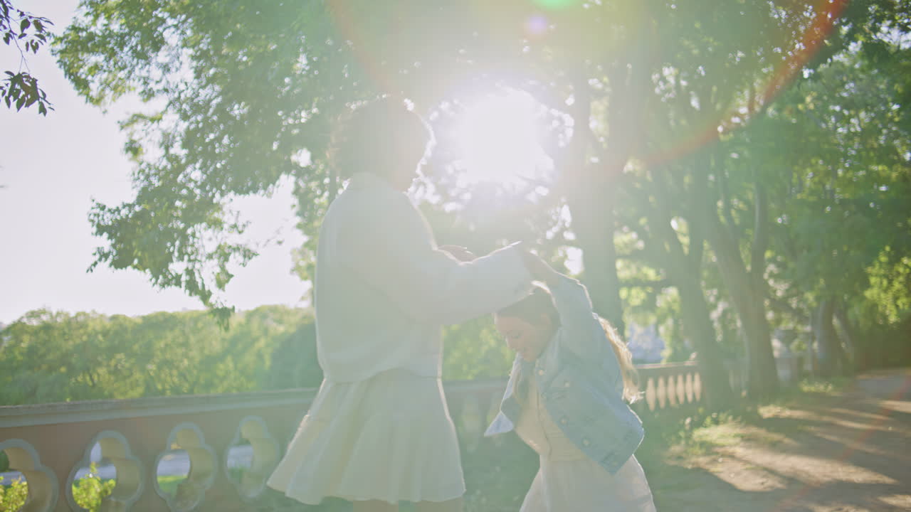 Carefree woman girl spinning sunshine park. Young mother swirling with daughter