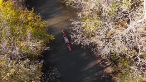 Hombre-Y-Mujer-Con-Canoa-Avanzan-En-El-Río-En-Otoño,-Drone-Sigue-Desde-El-Aire-Pavo-Iğneada