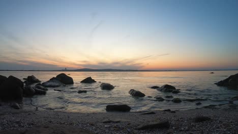 time lapse at golden sunset from the black sea coast. mussels on the shore. rocks in the sea water, fishing boat, clouds. romantic yellow and orange landscape