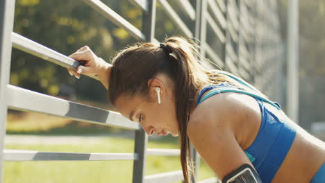 夏の日の屋外コートでのトレーニングの後、airpods を休ませ、激しく呼吸している疲れたスポーツウーマンの側面図