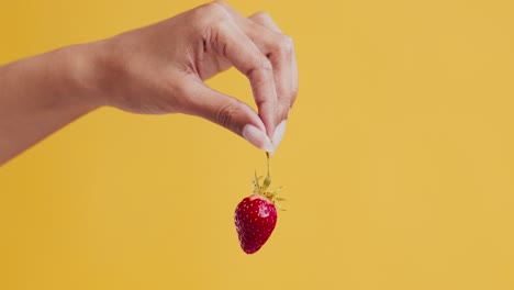 hand holding a strawberry