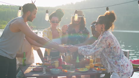 joyous friends enjoying hot dogs on lake party