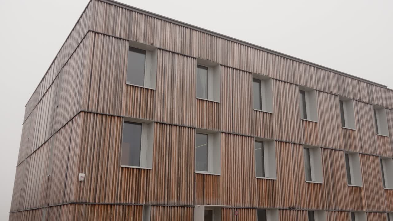 L'edificio presenta una moderna facciata in legno sostenibile utilizzata in costruzioni ecocompatibili.