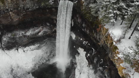 Magnificent-Water-Cascade-Of-Brandywine-Falls-In-Whistler,-Canada-With-Snow-covered-Rainforest-In-Winter