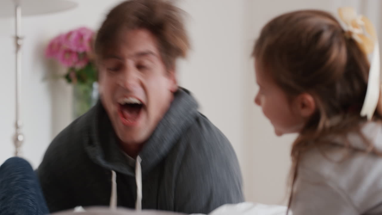 행복한 가족과 아이들이 침대에 뛰어들고 엄마와 아빠와 함께 놀고 주말 아침에 재미를 느끼고 흥분된 어린 아이들이 부모와 함께 집에서 게임을 즐기고 있습니다. 4k