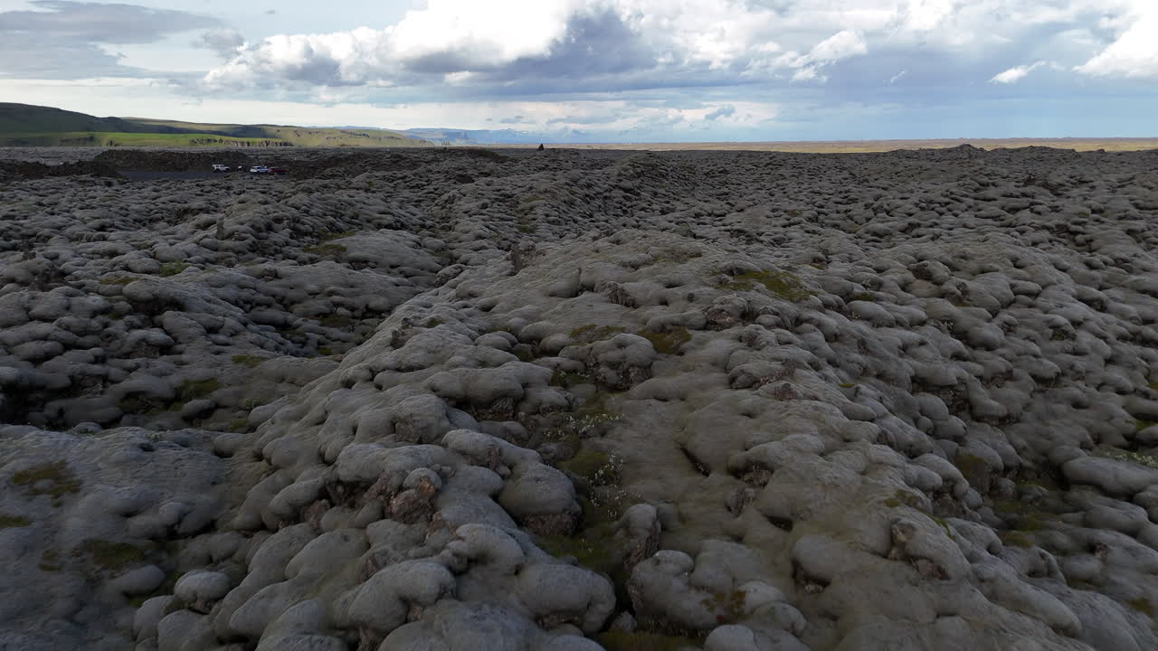Vue aérienne lumineuse du vaste champ de lave recouvert de mousse d’Islande sous des nuages épars, mettant en valeur des textures volcaniques uniques et la beauté sauvage des hautes terres.