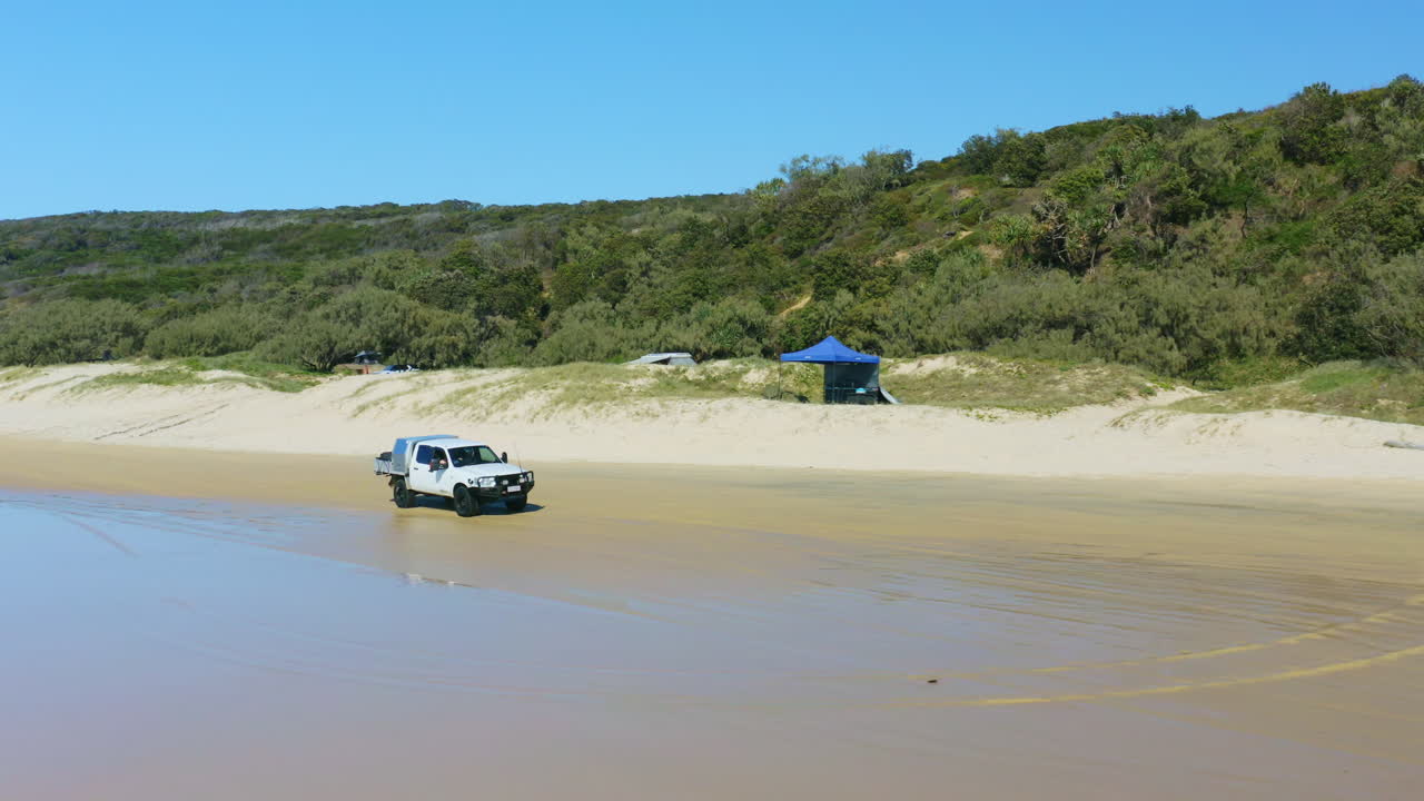 더블 아일랜드 포인트, 퀸즐랜드, 4k 드론에 있는 캠프장을 지나 모래 해변을 따라 운전하는 4wd 자동차