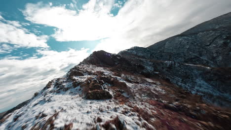 A-snow-capped-mountain-ridge-on-a-partly-cloudy-day,-aerial-view