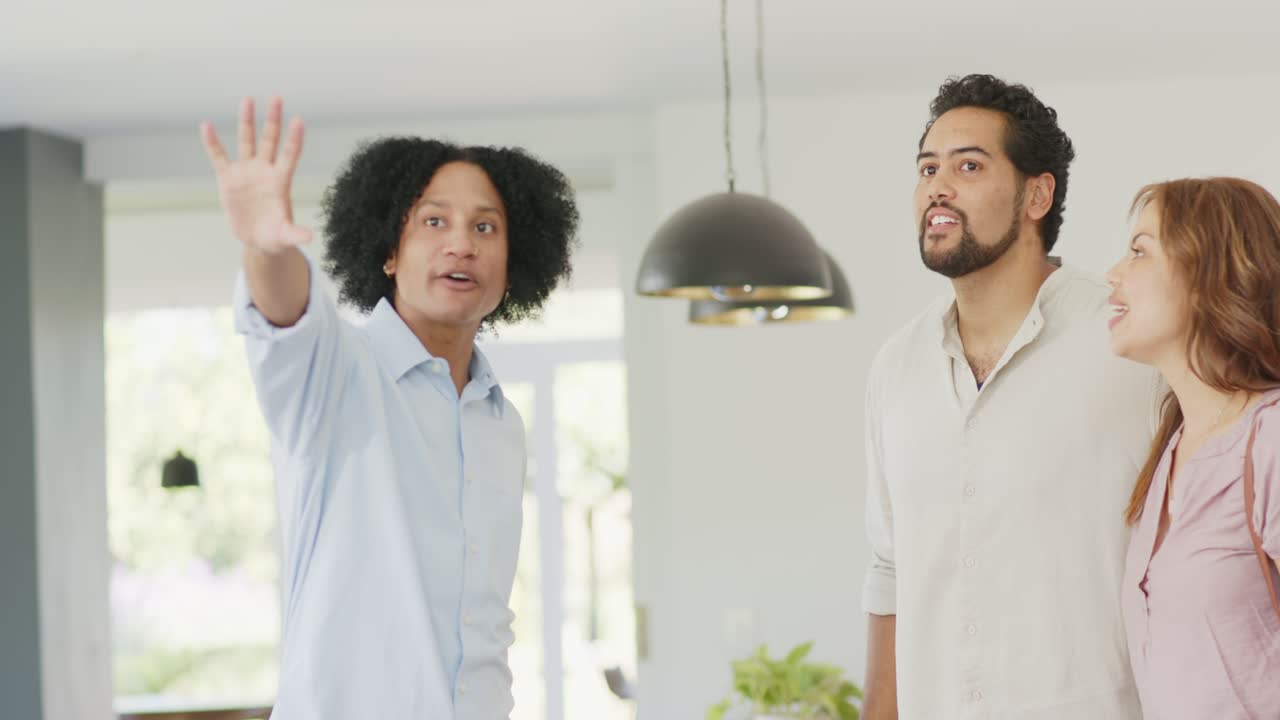 African American man agent as couple arriving guiding in home pointing lights and file showing hei