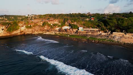 sunset drone footage of balangan beach in bali reveals the contrast between rocky cliffs and calm ocean waves creating a peaceful and breathtaking coastal evening view