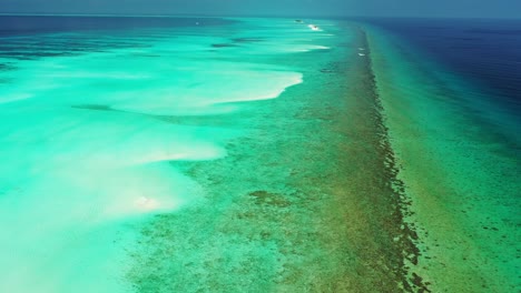 Beautiful-scenery-of-tropical-paradise-with-shiny-turquoise-lagoon,-brown-coral-reefs-and-deep-blue-ocean-in-Caribbean