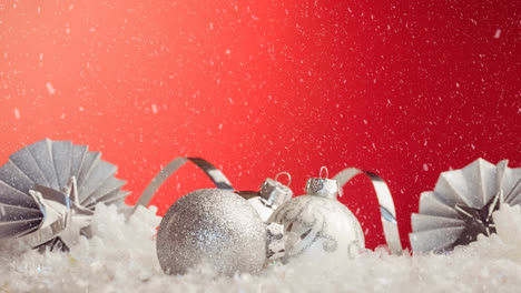 Animation-of-snow-falling-over-baubles-on-red-background
