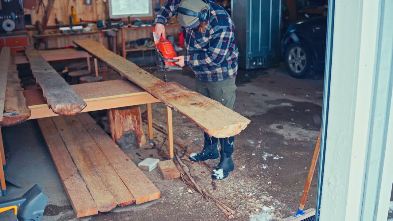 A Man Uses a Chainsaw to Cut Through Timber in the Process of Making a Rustic Bench - Close Up