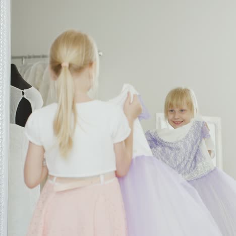 7 years old girl trying on elegant dress in front of a mirror