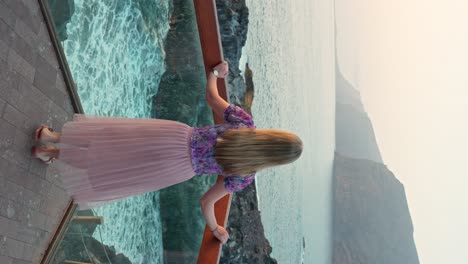 Vertical-shot-of-woman-leaning-over-balcony-terrace-by-the-sea-in-Tenerife