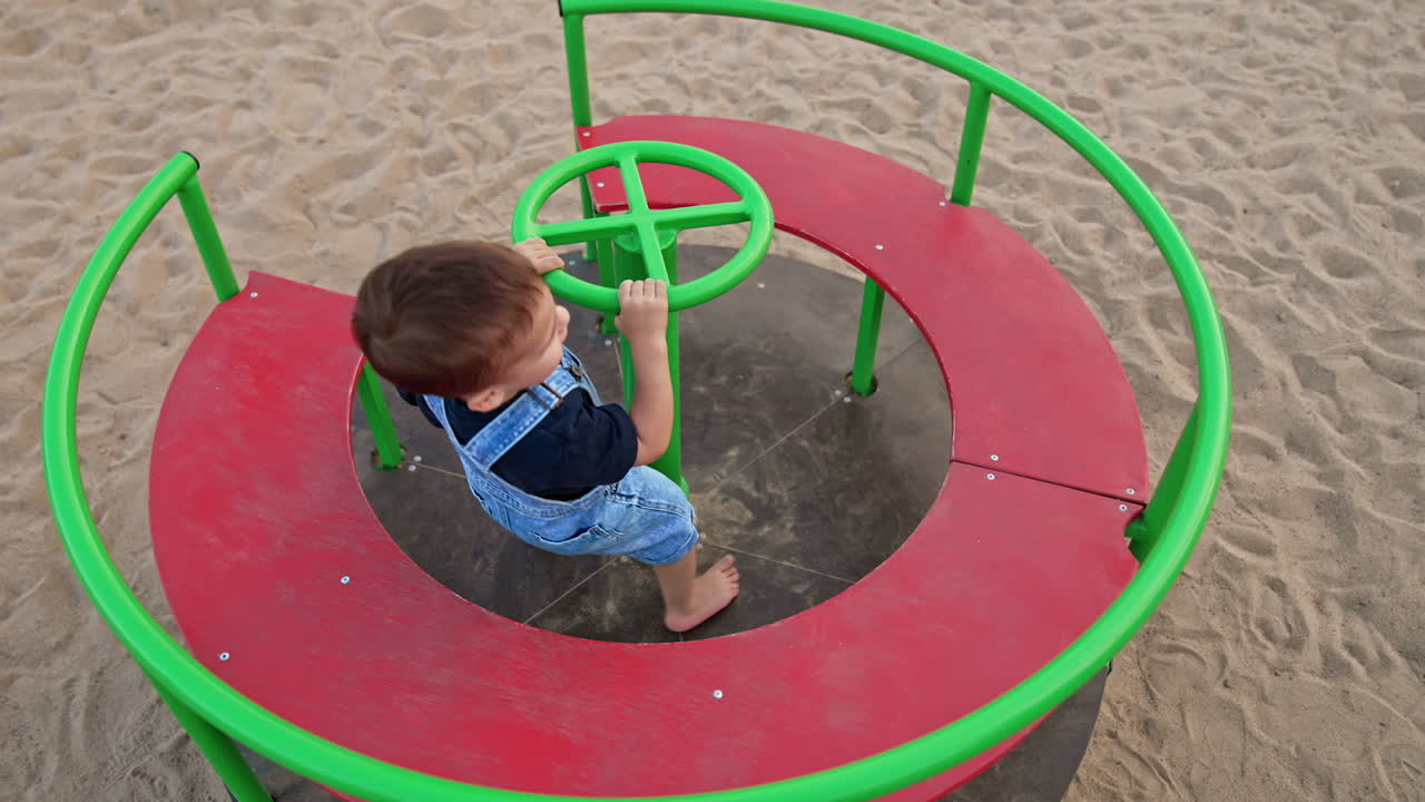 Child playing on a playground carousel in the sand