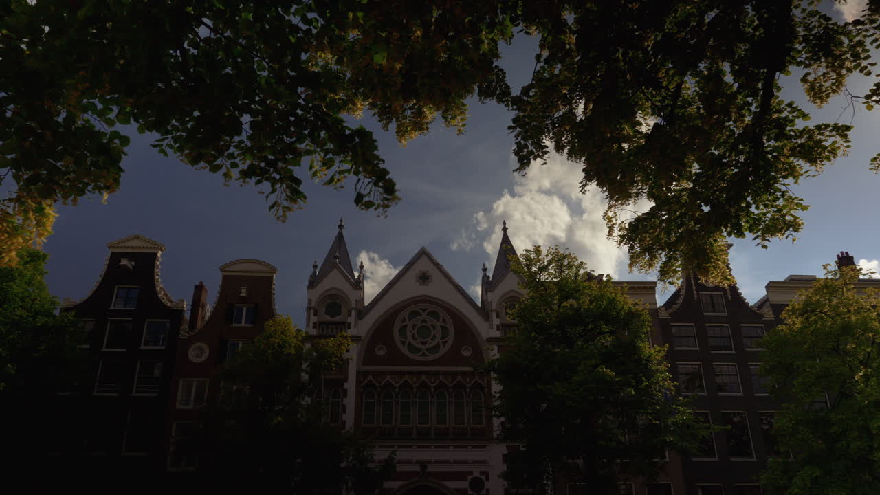 태양이 구름 뒤에서 정점을 찍는 동안 암스테르담의 오래된 건물을 올려다 봅니다.