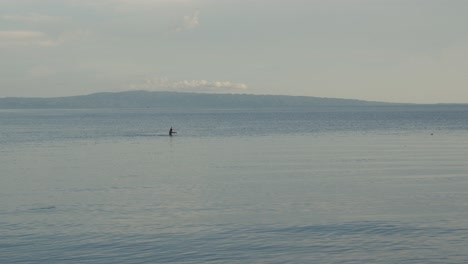 Person-from-village-in-Philippines-fishing-in-the-ocean-with-mountains-in-the-background-during-sunrise