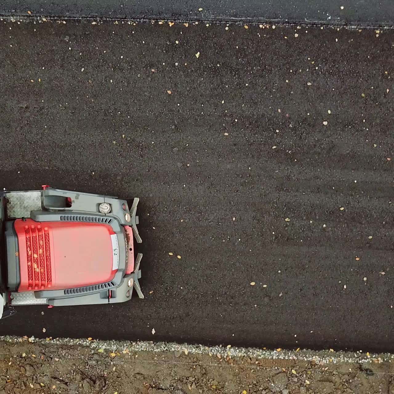 Aerial view of a truck at roadworks. Top view of asphalt compactor pressuring the new road outside. Slow motion.