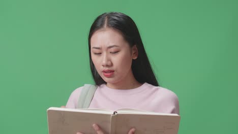asian woman student reading a book and having headache in green screen studio