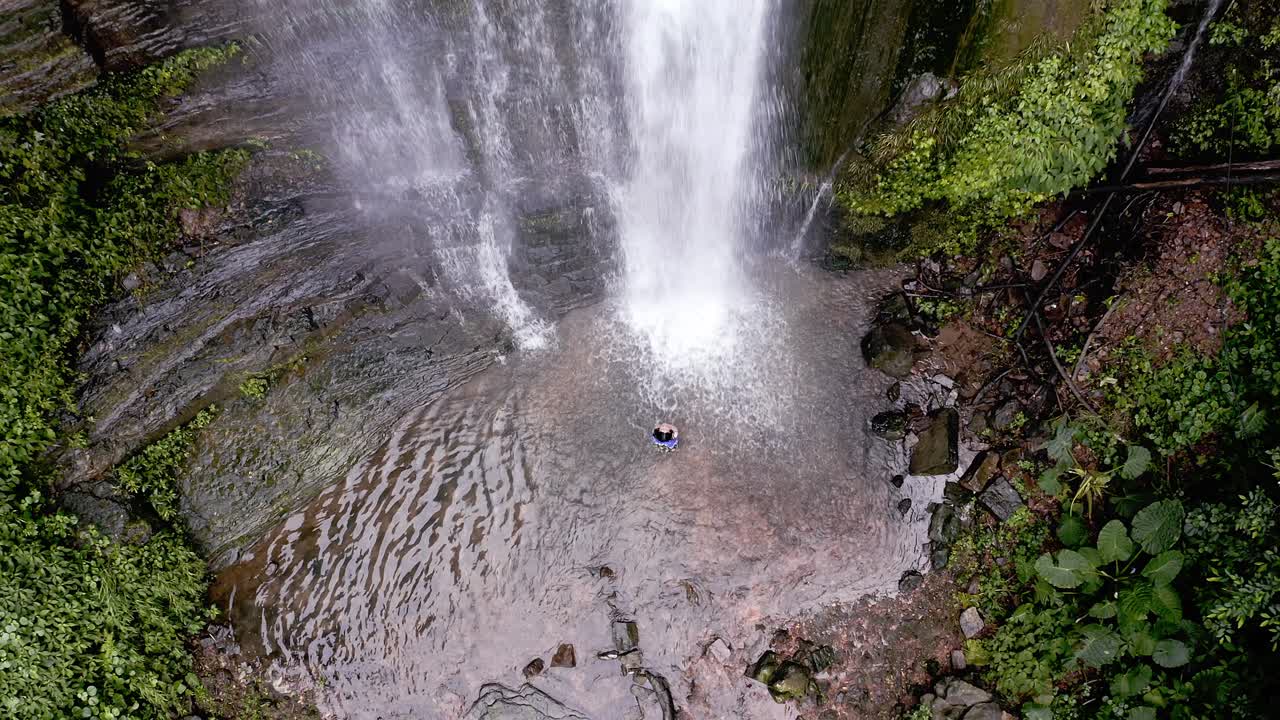 Woman showering in Pubutang Waterfall, rising aerial view, China karst mountain