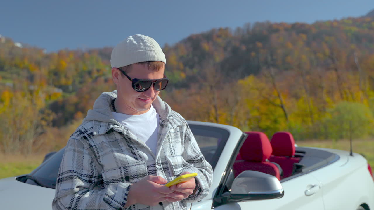 Man using phone in convertible car near mountains