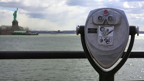 a coin operated viewer looks out at the statue of liberty in new york harbor