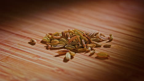 fennel seeds on a wooden surface with dramatic lighting, camera orbiting