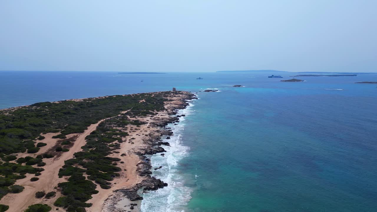 Turquoise waves crashing on the rocky coast of Ses Salines beach with the ancient watchtower. Wonderful aerial view flight speed ramp hyper motion time lapse