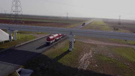 remolques en carretera asfaltada en reynosa, tamaulipas, méxico con un puente en un día soleado, tiro de drones 4k