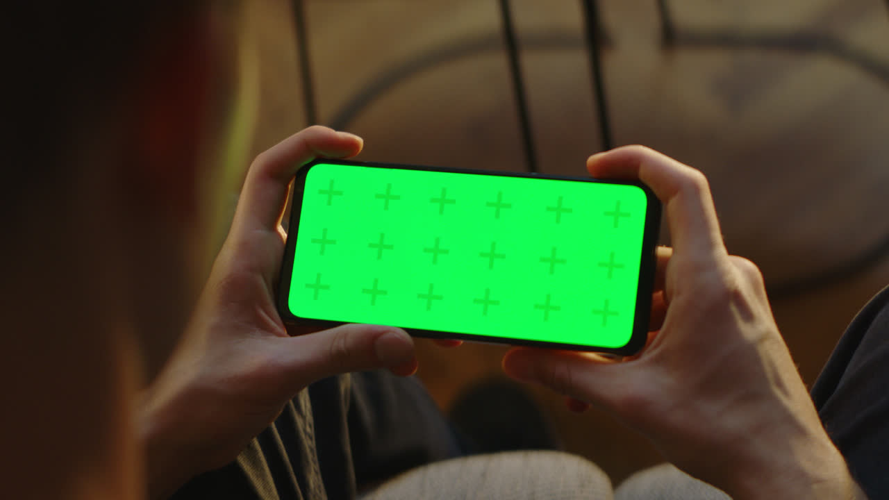 초록색 화면의 스마트폰을 사용하는 사람