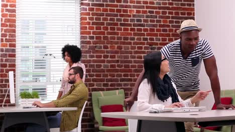casual businesswoman talking with colleague at her desk