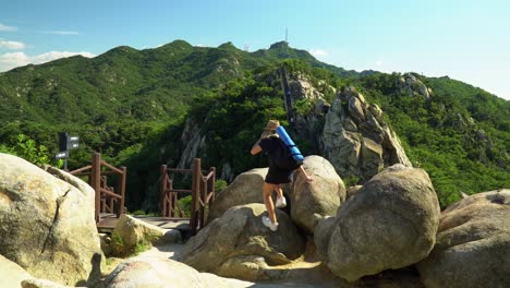 girl walking towards the boulders and almost slipped when climbing - girl standing on the rocks and enjoying the natural view from gwanaksan mountain with open arms overhead