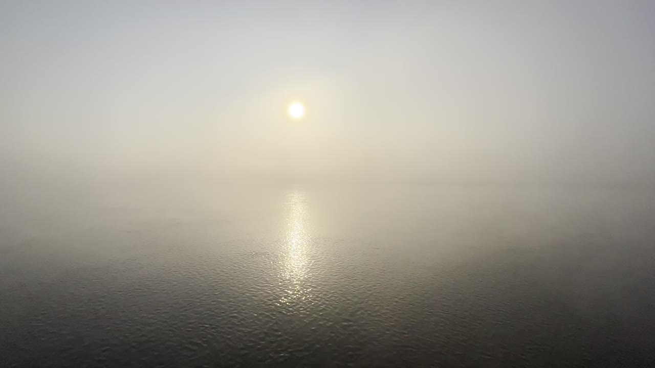 태양의 반사와 함께 흐르는 물체 위에 찍힌 아침 안개 속에서 해가 뜨는 광범위한 정적