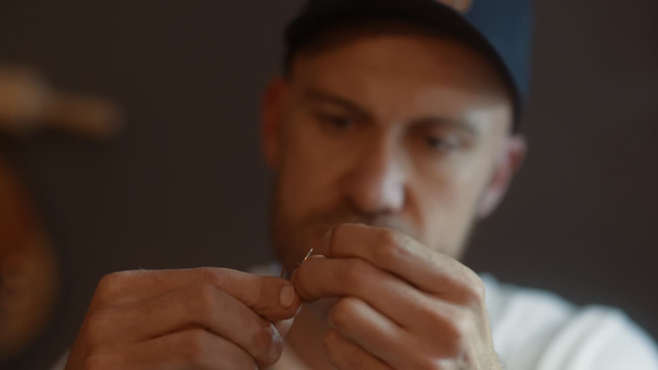 Close up of artisan threading a needle for sewing leatherwork