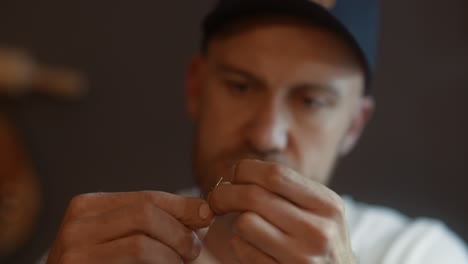 close up of artisan threading a needle for sewing leatherwork