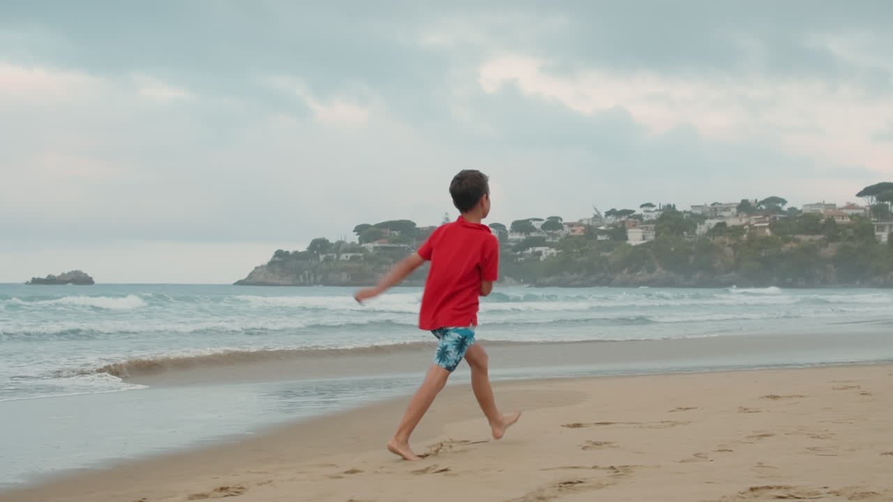 Relaxed boy enjoying summer at beach. Carefree guy skipping at coastline.