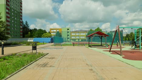 Entry-dolly-shot-of-empty-kids-playground-with-sandbox,-swing-in-the-house-estate