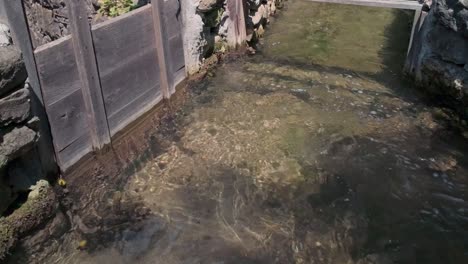 clean clear river water flowing along channel construction with wooden sluice gate